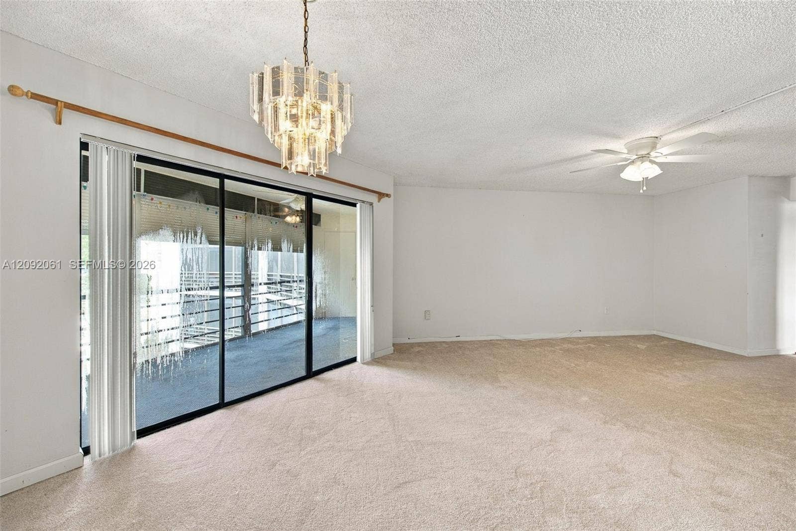 6555 W Broward Boulevard, #309, Plantation, FL 33317 Living space featuring wall-to-wall carpeting, floor-to-ceiling sliding glass doors, a decorative multi-tiered chandelier, and a ceiling fan with integrated lighting