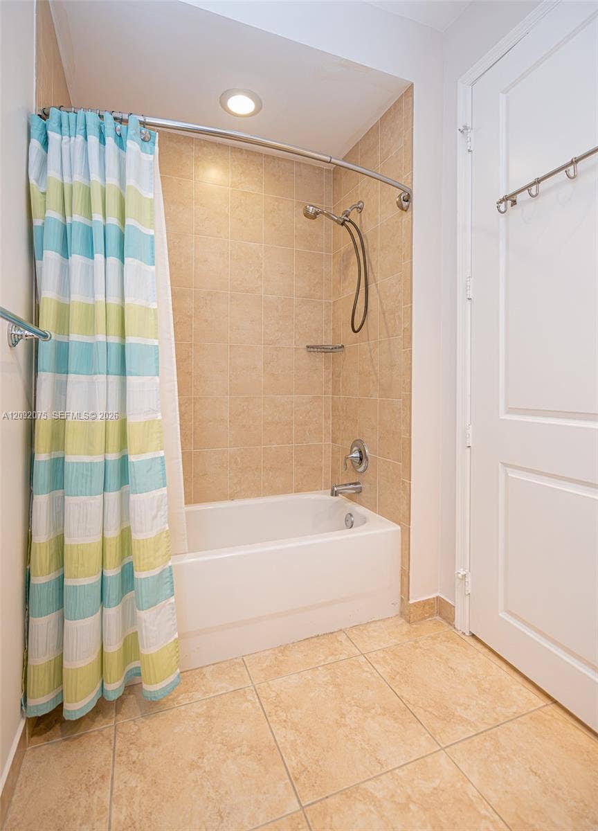 3055 NW 126th Avenue, #219, Sunrise, FL 33323 Built-in bathtub with a tile surround, curved shower rod, recessed ceiling lighting, and large format tile flooring