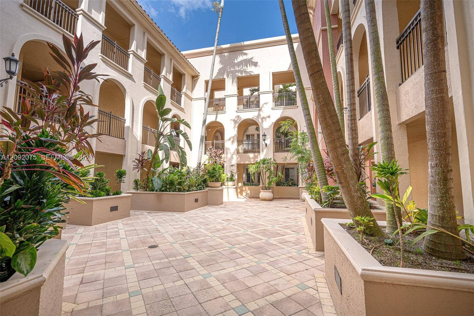 3055 NW 126th Avenue, #219, Sunrise, FL 33323 Courtyard with paver flooring, multiple raised planters with mature foliage, and arched architectural details