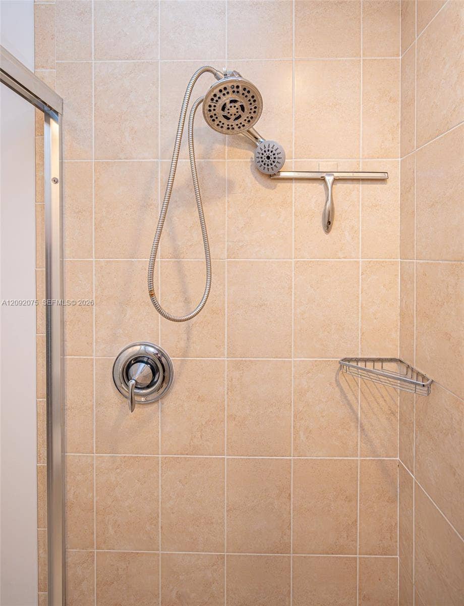 3055 NW 126th Avenue, #219, Sunrise, FL 33323 Beige square tile shower surround with a handheld showerhead, chrome fixtures, and a corner shower caddy