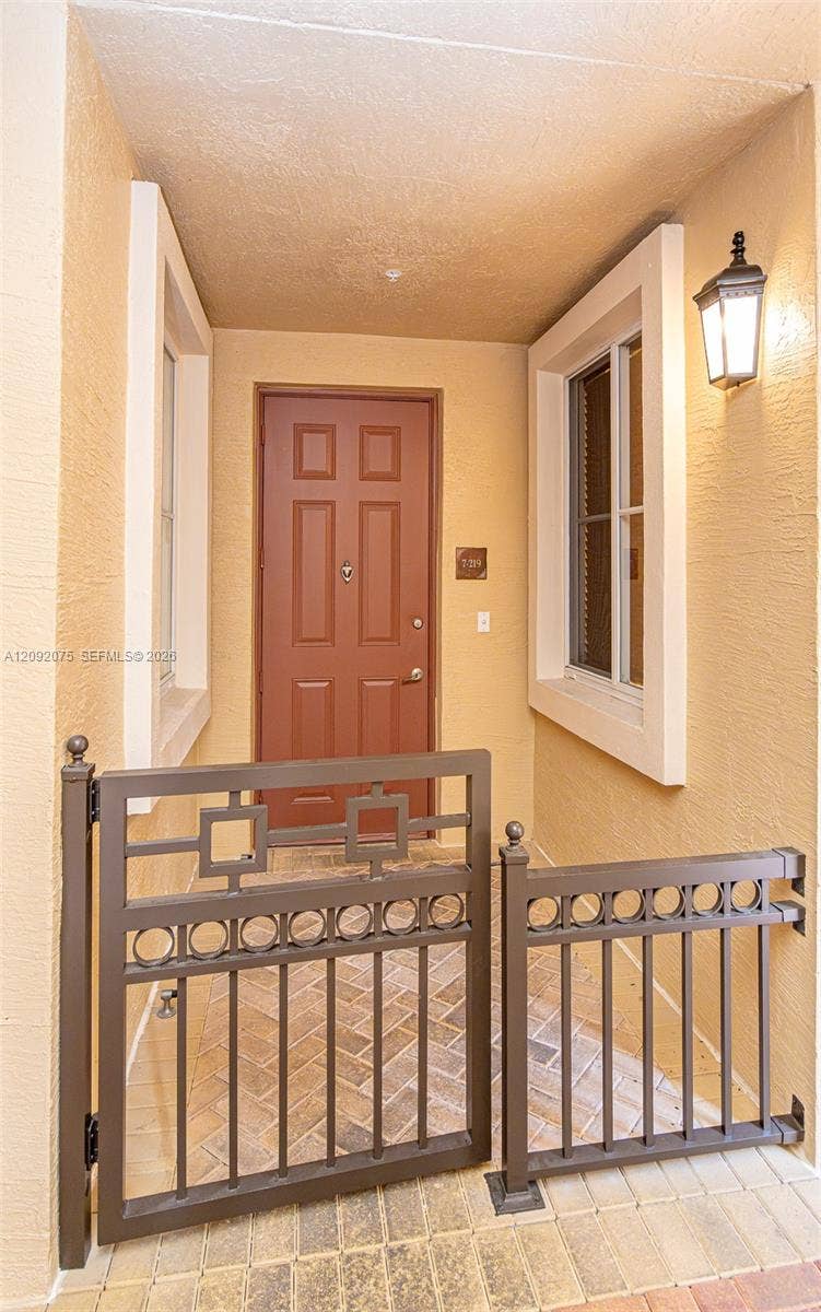 3055 NW 126th Avenue, #219, Sunrise, FL 33323 Entryway featuring a brown panel door, decorative metal gate, and brick-patterned hardscaping