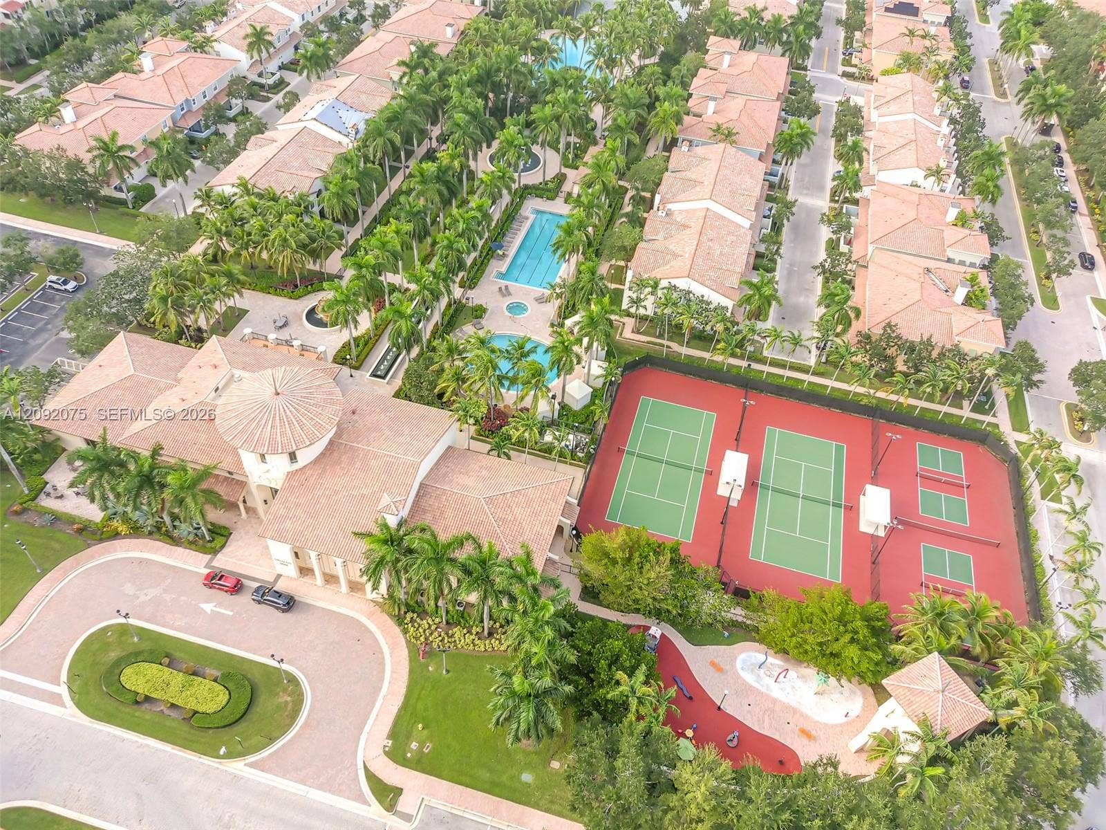 3055 NW 126th Avenue, #219, Sunrise, FL 33323 Expansive community grounds featuring a tennis court, two swimming pools, a clubhouse with a circular tower, and a designated splash pad area