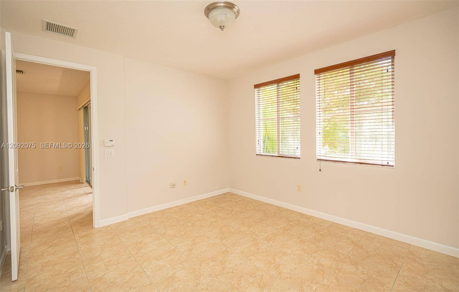 3055 NW 126th Avenue, #219, Sunrise, FL 33323 Tiled flooring, two windows with blinds, a flush mount light fixture, and a neutral wall finish