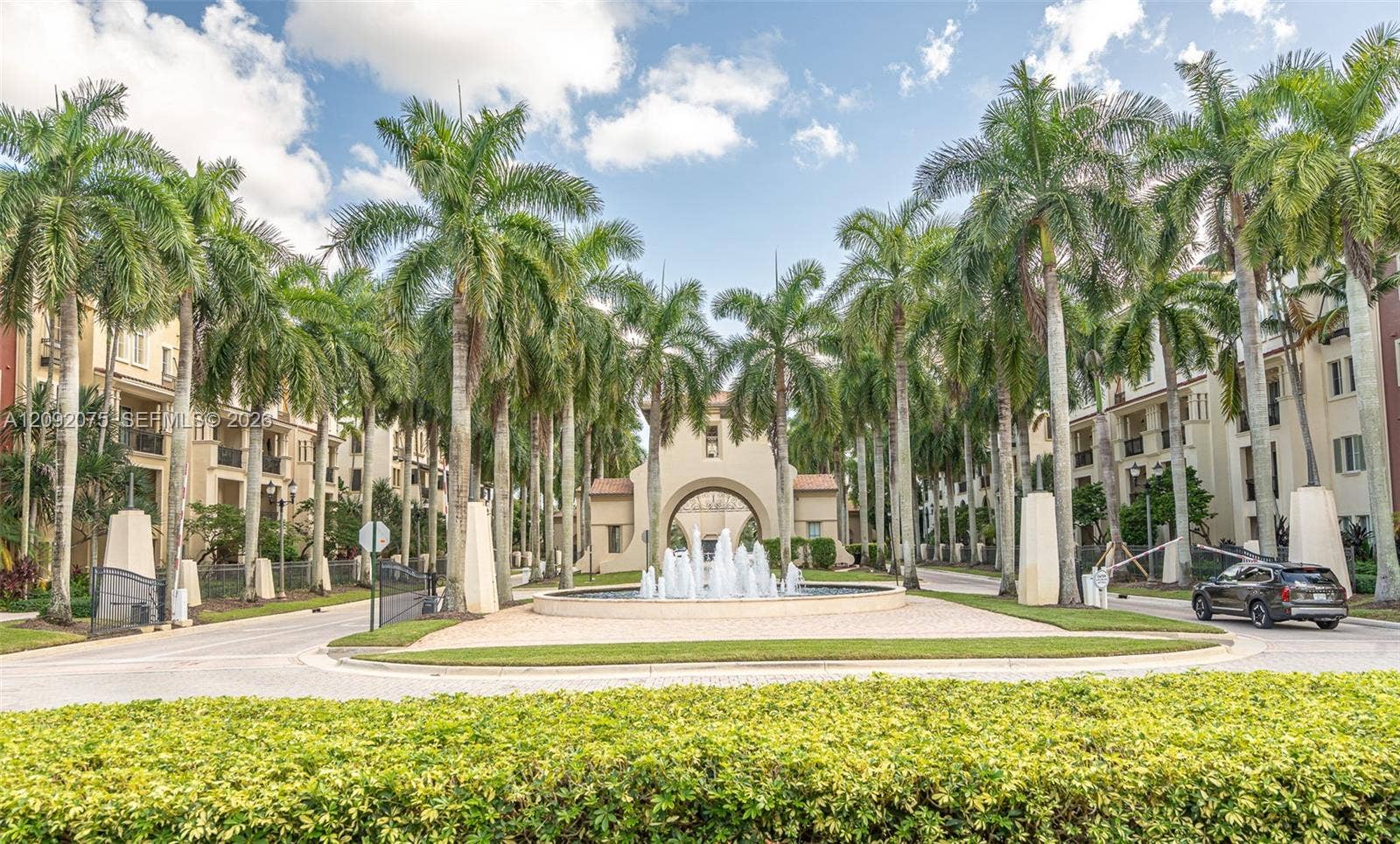 3055 NW 126th Avenue, #219, Sunrise, FL 33323 Grand entry featuring a central fountain, lush landscaping, and mature palm trees