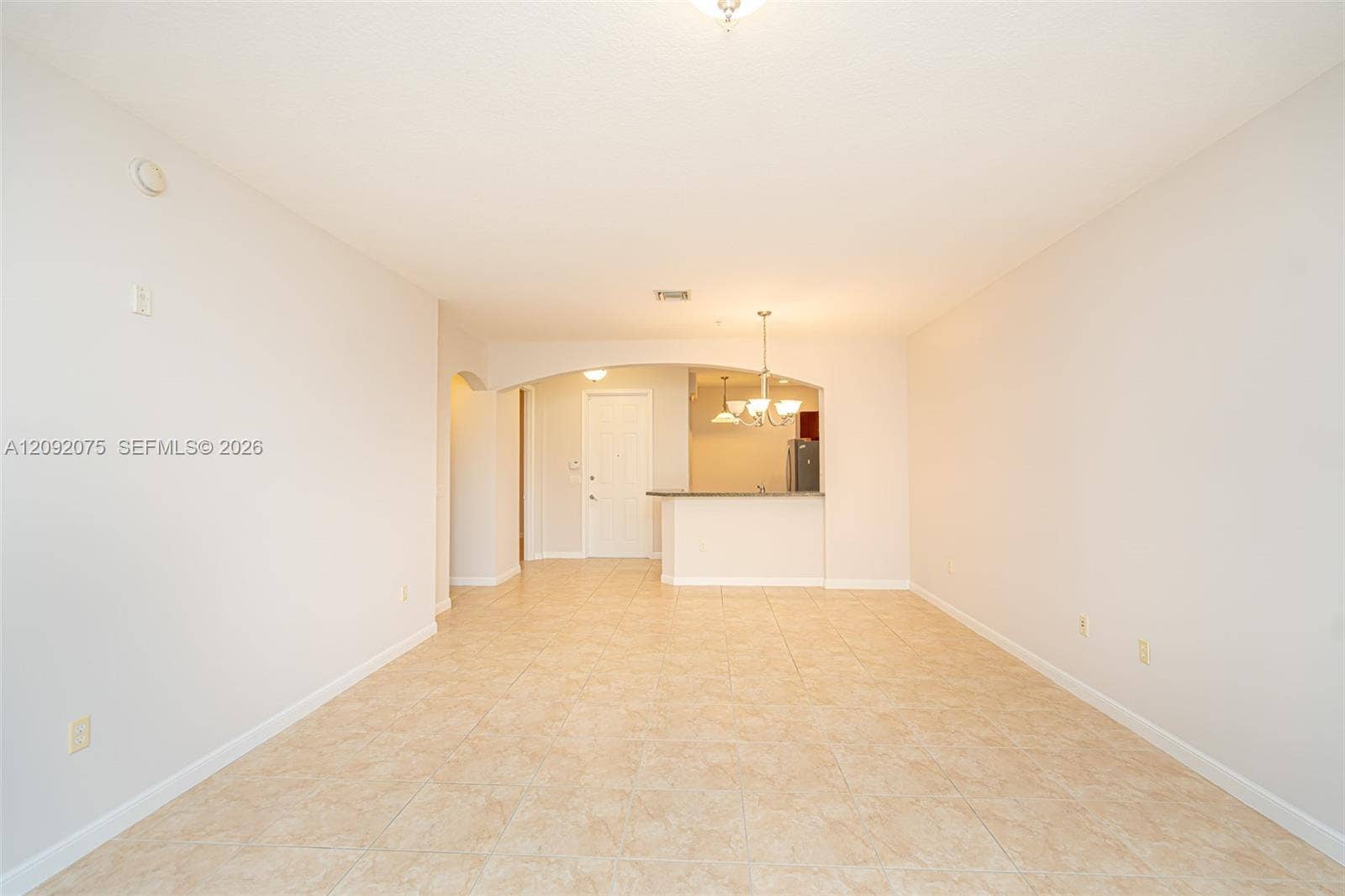 3055 NW 126th Avenue, #219, Sunrise, FL 33323 Tile flooring throughout, neutral wall tones, arched doorway, and a kitchen pass-through with a breakfast bar