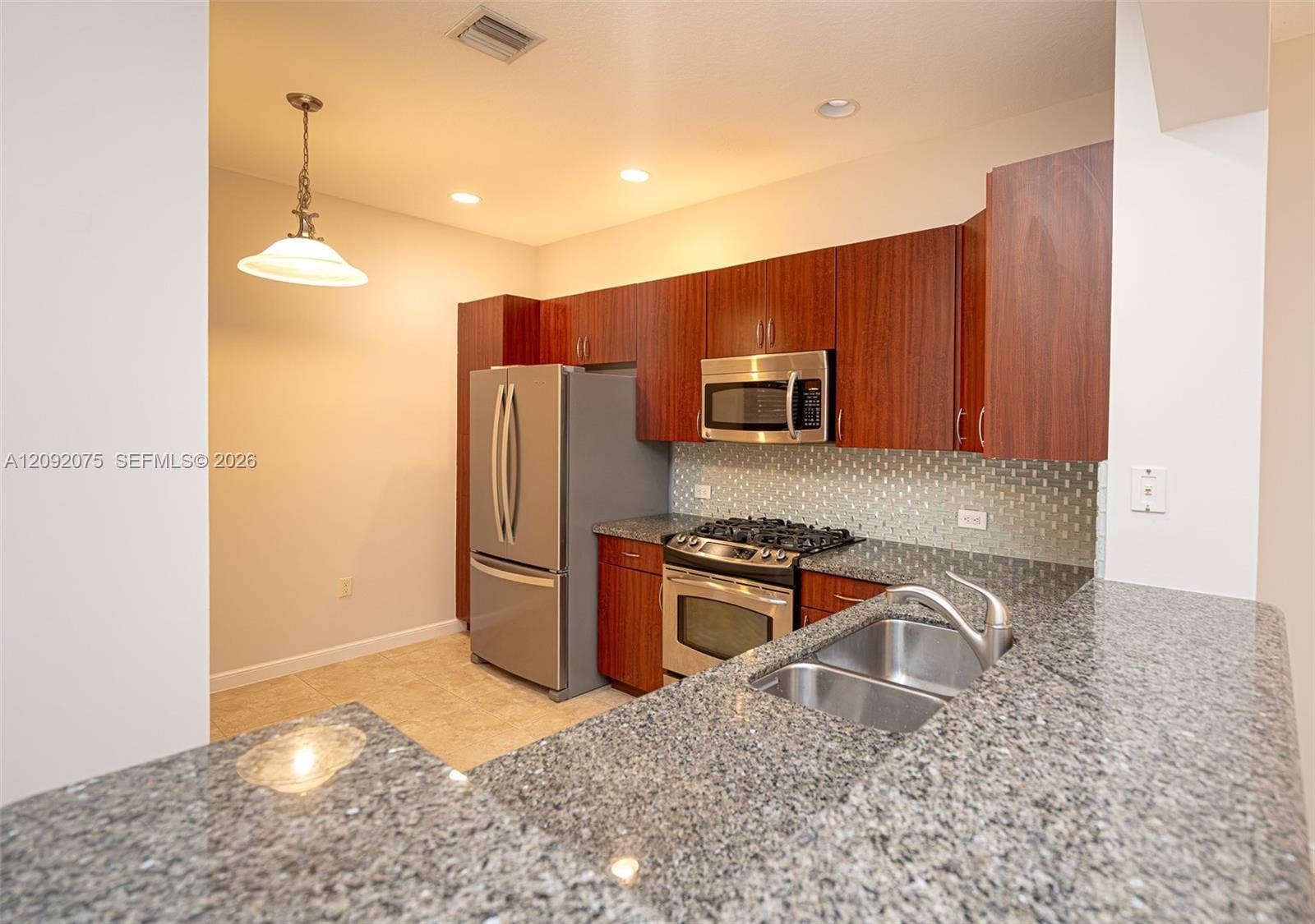 3055 NW 126th Avenue, #219, Sunrise, FL 33323 Kitchen featuring wood cabinetry, stainless steel appliances, a tile backsplash, granite countertops, and recessed lighting