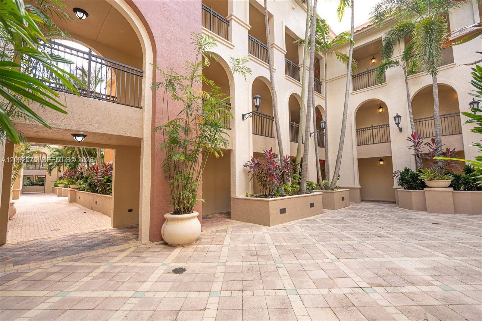 3055 NW 126th Avenue, #219, Sunrise, FL 33323 Courtyard entry with paver flooring, arched walkways, decorative iron railings, and integrated planter beds