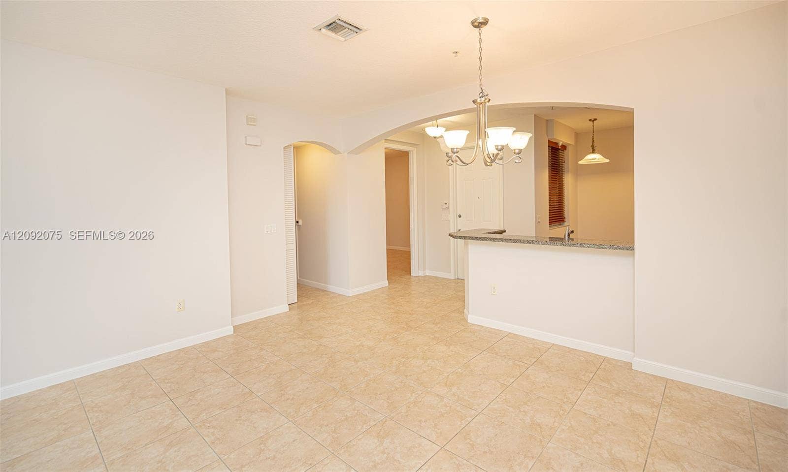 3055 NW 126th Avenue, #219, Sunrise, FL 33323 Tiled flooring throughout, arched doorways, a built-in breakfast bar with a stone countertop, and an overhead chandelier light fixture