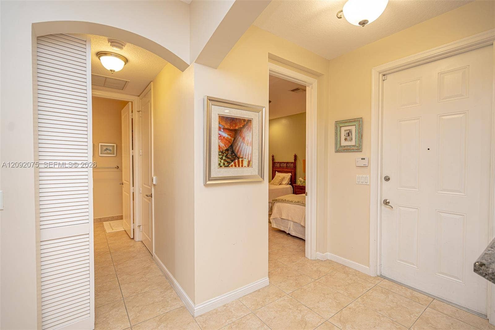 3055 NW 126th Avenue, #219, Sunrise, FL 33323 Foyer featuring tiled flooring, a white paneled entry door, arched doorway, and built-in overhead lighting