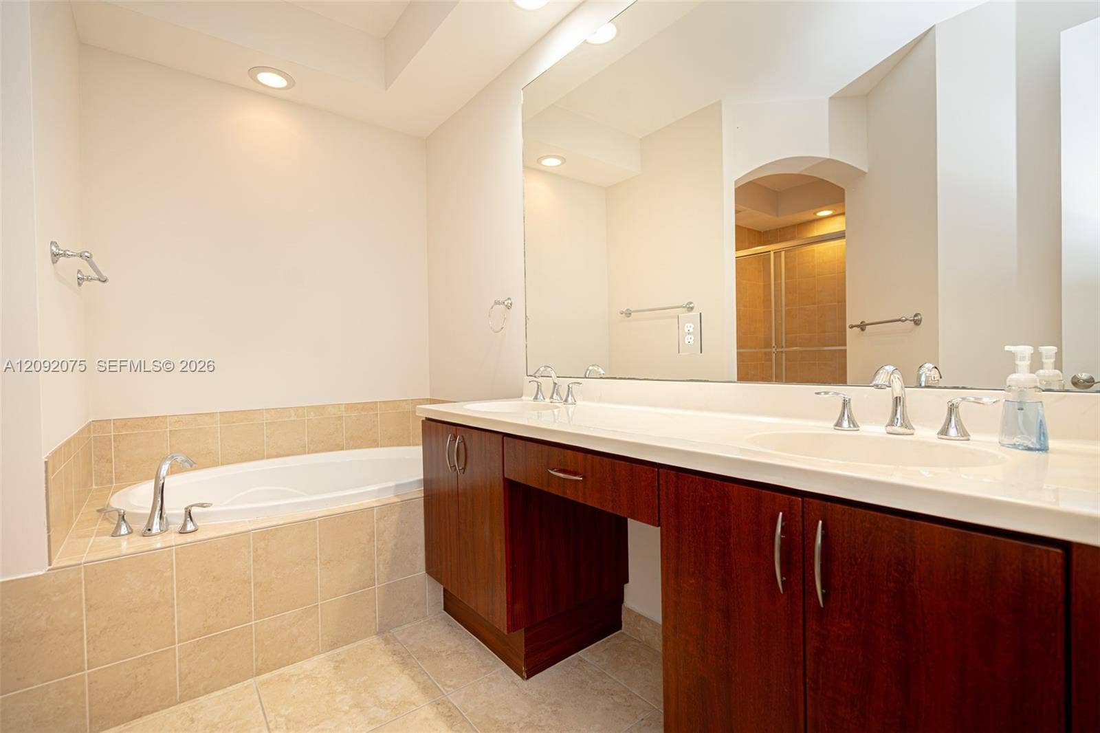 3055 NW 126th Avenue, #219, Sunrise, FL 33323 Dual vanity with integrated sinks, recessed lighting, built-in soaking tub with tile surround, and wood-finish cabinetry