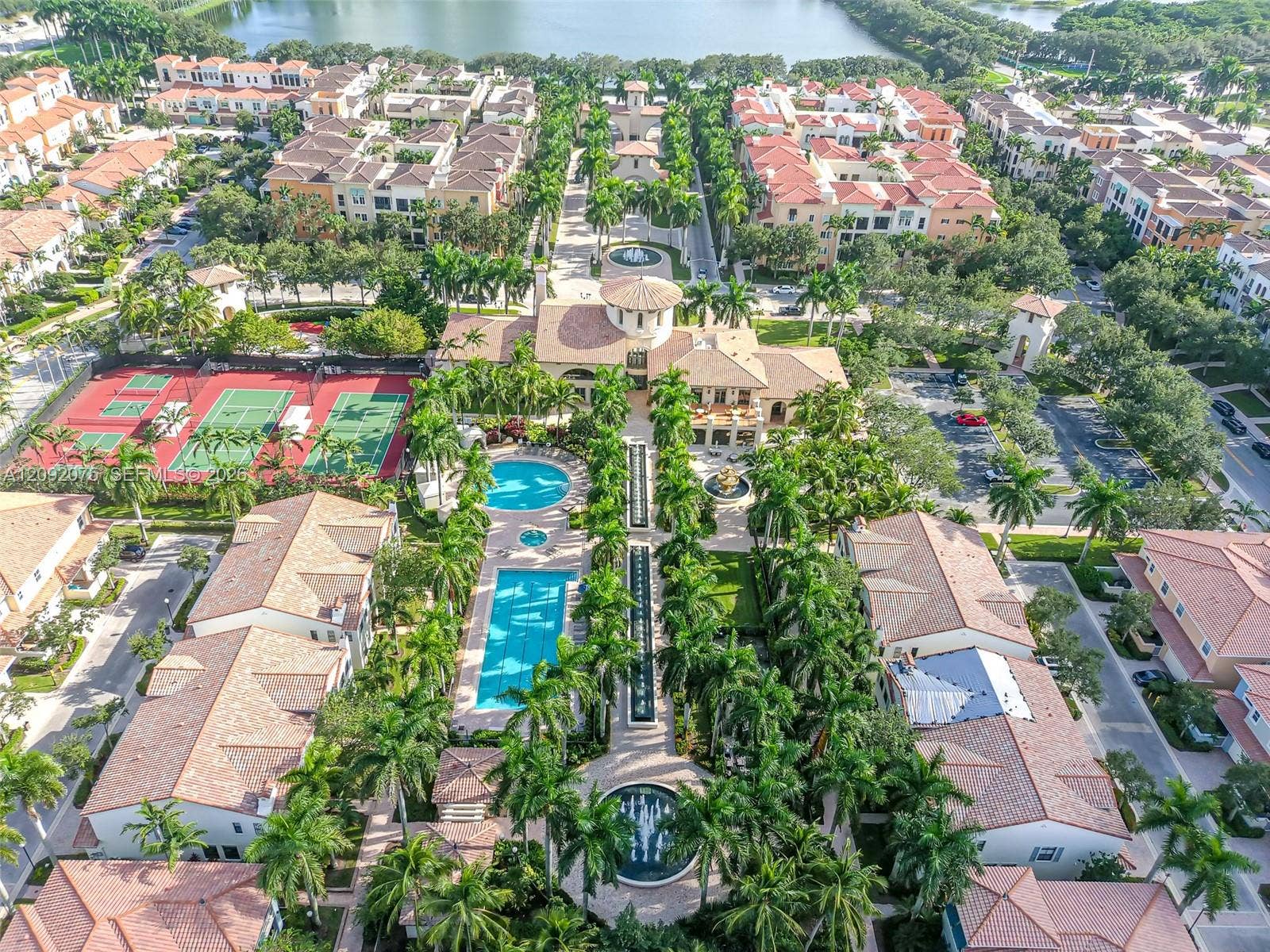 3055 NW 126th Avenue, #219, Sunrise, FL 33323 Aerial perspective featuring a central building with a rotunda, two swimming pools, multiple tennis courts, and mature palm trees