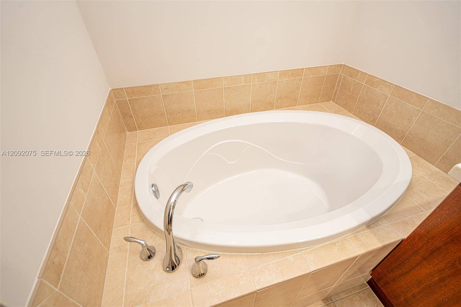 3055 NW 126th Avenue, #219, Sunrise, FL 33323 Oval drop-in bathtub with a deck-mounted chrome faucet, surrounded by neutral-toned square tile