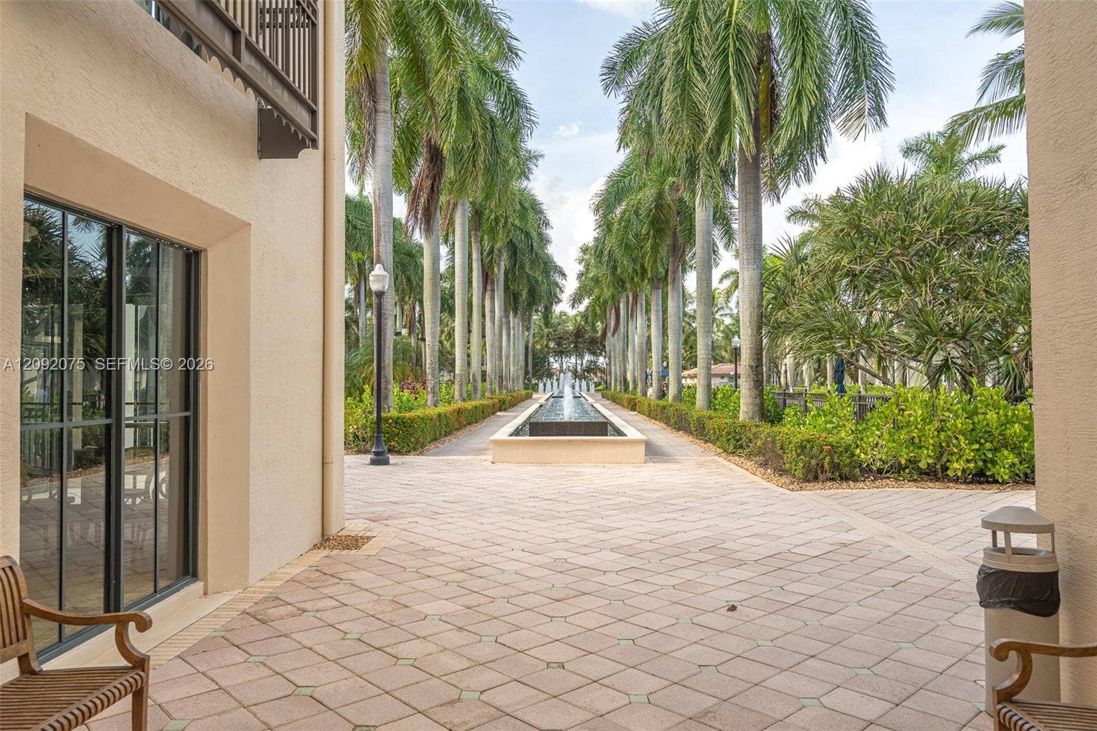 3055 NW 126th Avenue, #219, Sunrise, FL 33323 Paved walkway featuring a central water feature, manicured hedges, and mature palm trees