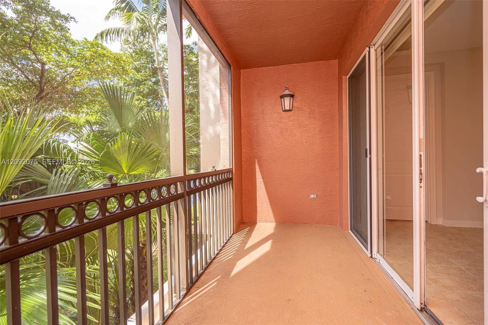 3055 NW 126th Avenue, #219, Sunrise, FL 33323 Balcony featuring a decorative metal railing, exterior wall sconce, and sliding glass doors