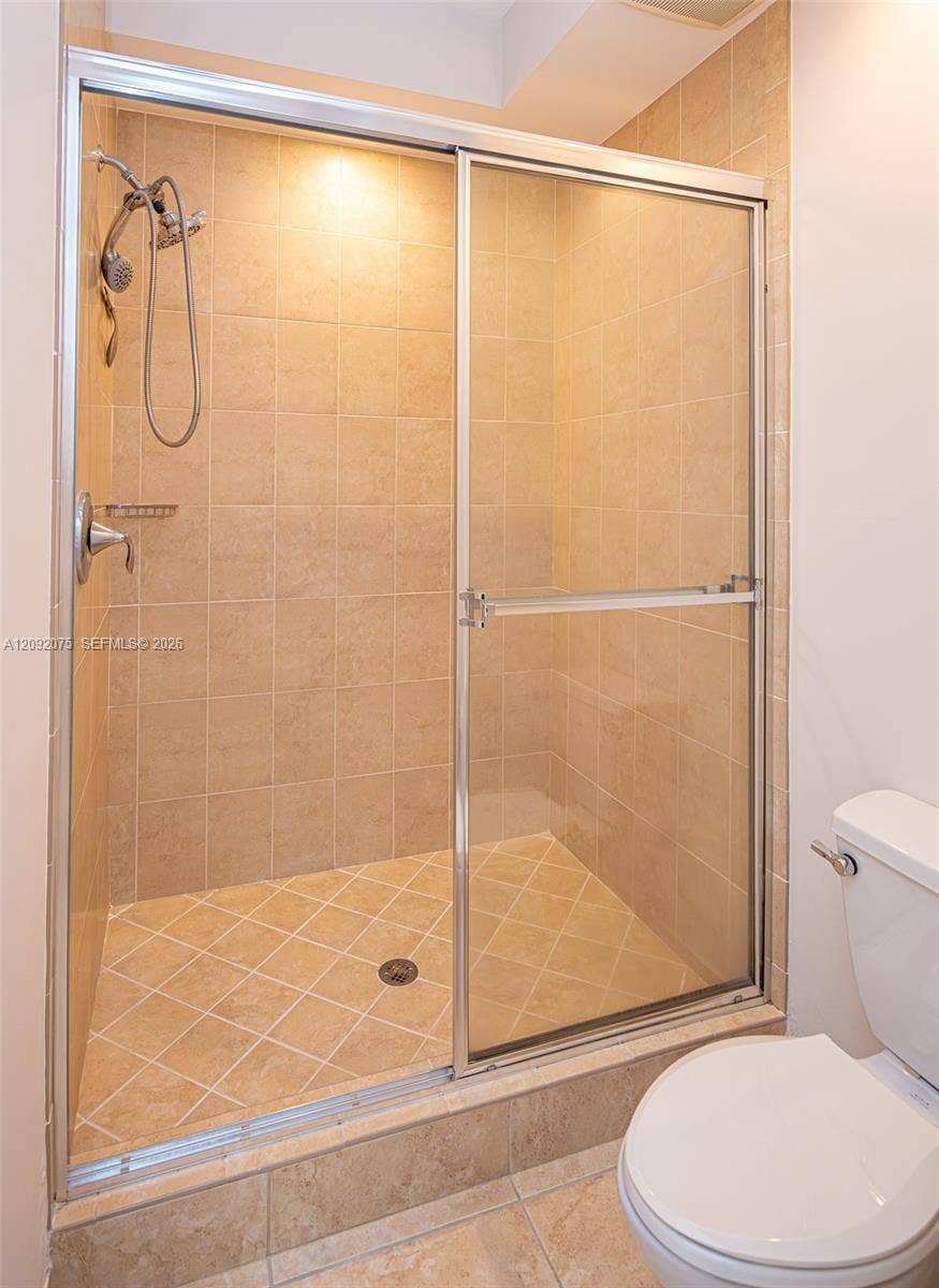3055 NW 126th Avenue, #219, Sunrise, FL 33323 Tiled shower with sliding glass enclosure, integrated shower head, and an overhead light fixture
