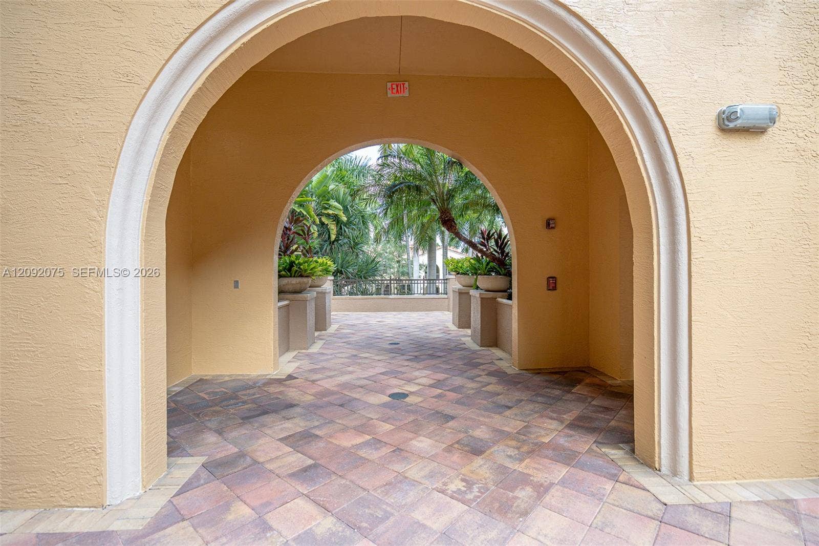 3055 NW 126th Avenue, #219, Sunrise, FL 33323 Archway entry with textured stucco finish and decorative trim, featuring an exterior walkway with paver flooring
