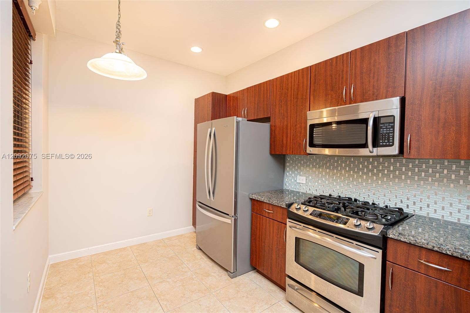 3055 NW 126th Avenue, #219, Sunrise, FL 33323 Stainless steel appliances, wood-finish cabinetry, tile flooring, glass mosaic tile backsplash, and recessed lighting
