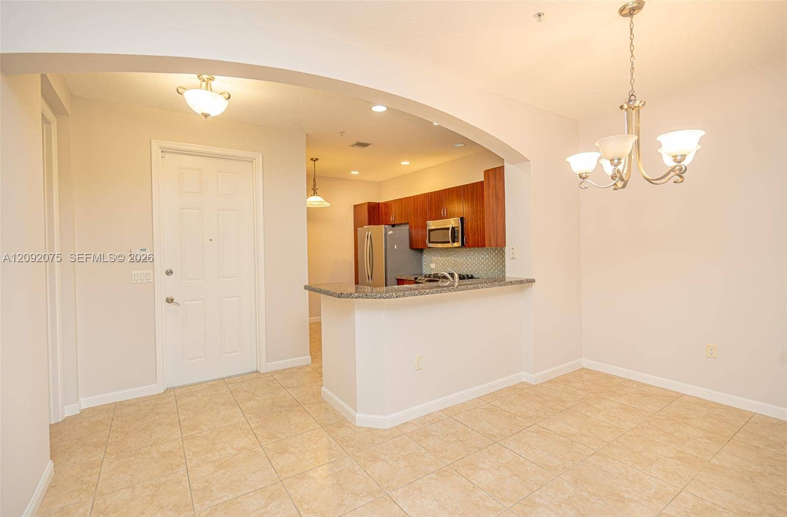 3055 NW 126th Avenue, #219, Sunrise, FL 33323 Tile flooring, arched entryway, pendant lighting, stainless steel appliances, and a breakfast bar with a stone countertop
