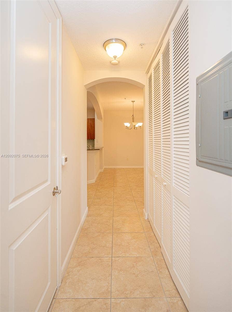 3055 NW 126th Avenue, #219, Sunrise, FL 33323 Hallway featuring square tile flooring, louvered bi-fold doors, and an arched doorway