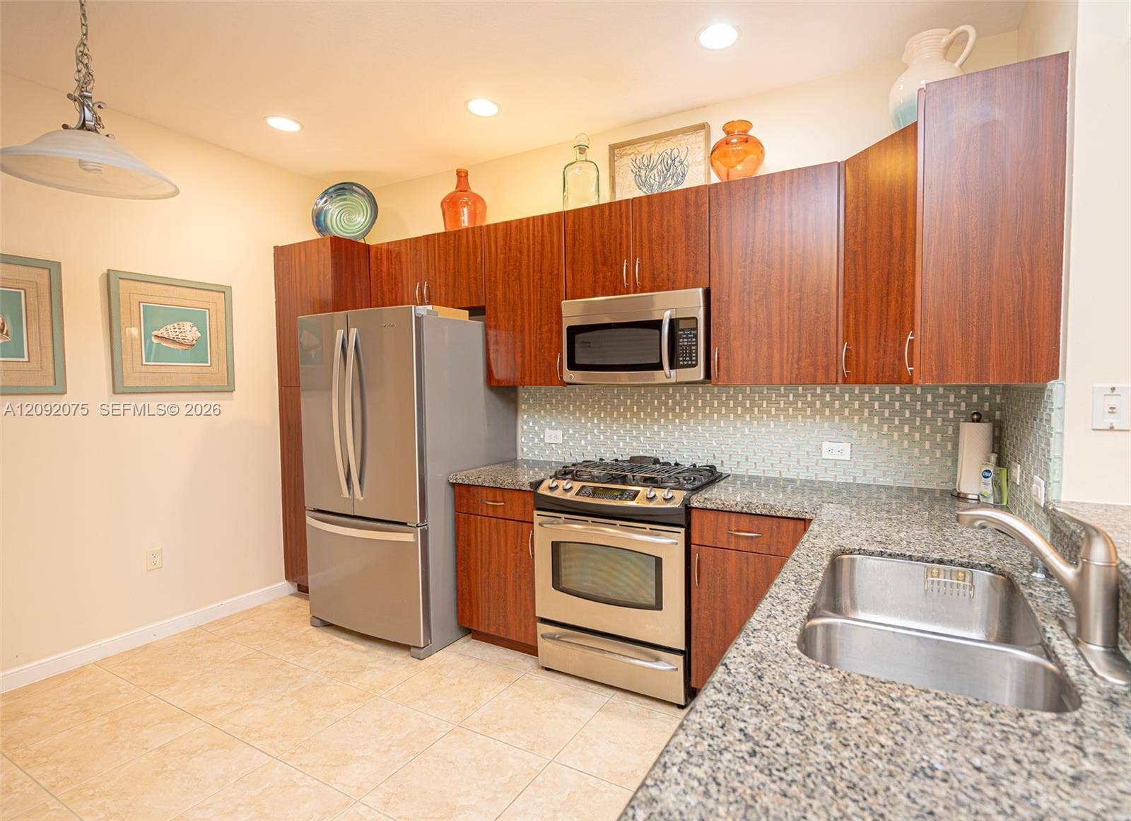 3055 NW 126th Avenue, #219, Sunrise, FL 33323 Kitchen featuring wood-finish cabinetry, stainless steel appliances, speckled stone countertops, a tile backsplash, and recessed lighting