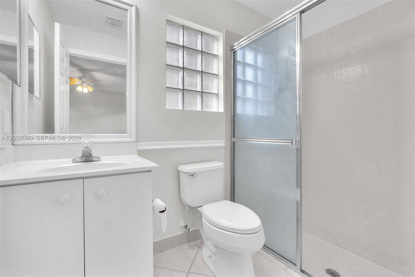 11979 SW 28th Court, Miramar, Miramar, FL 33025 Bathroom featuring a vanity with an integrated sink, glass block window, walk-in shower with a sliding enclosure, and ceramic tile flooring