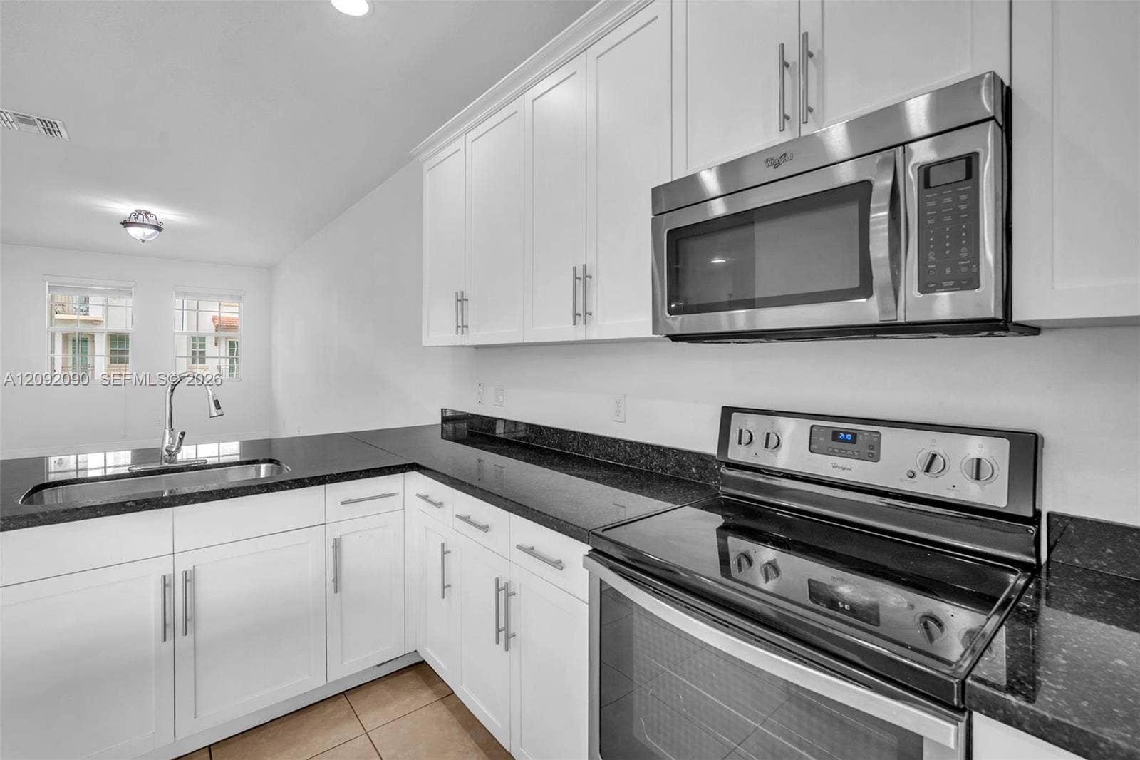 11979 SW 28th Court, Miramar, Miramar, FL 33025 Kitchen featuring white shaker-style cabinetry, dark stone countertops, stainless steel appliances, and an undermount sink with a high-arch pull-down faucet