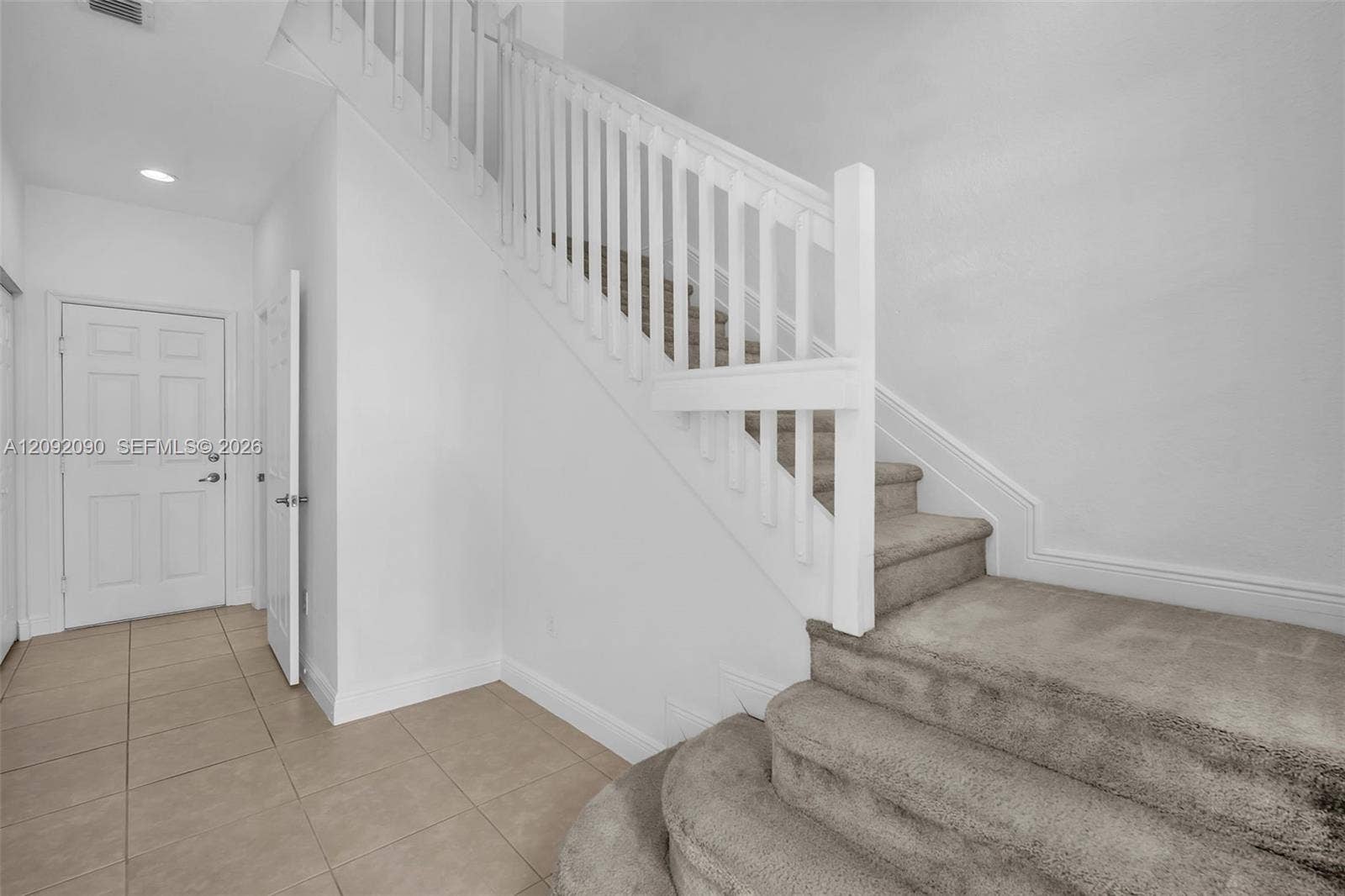 11979 SW 28th Court, Miramar, Miramar, FL 33025 Interior foyer featuring large-format tile flooring, a recessed lighting fixture, and a staircase with carpeted treads and a painted white balustrade