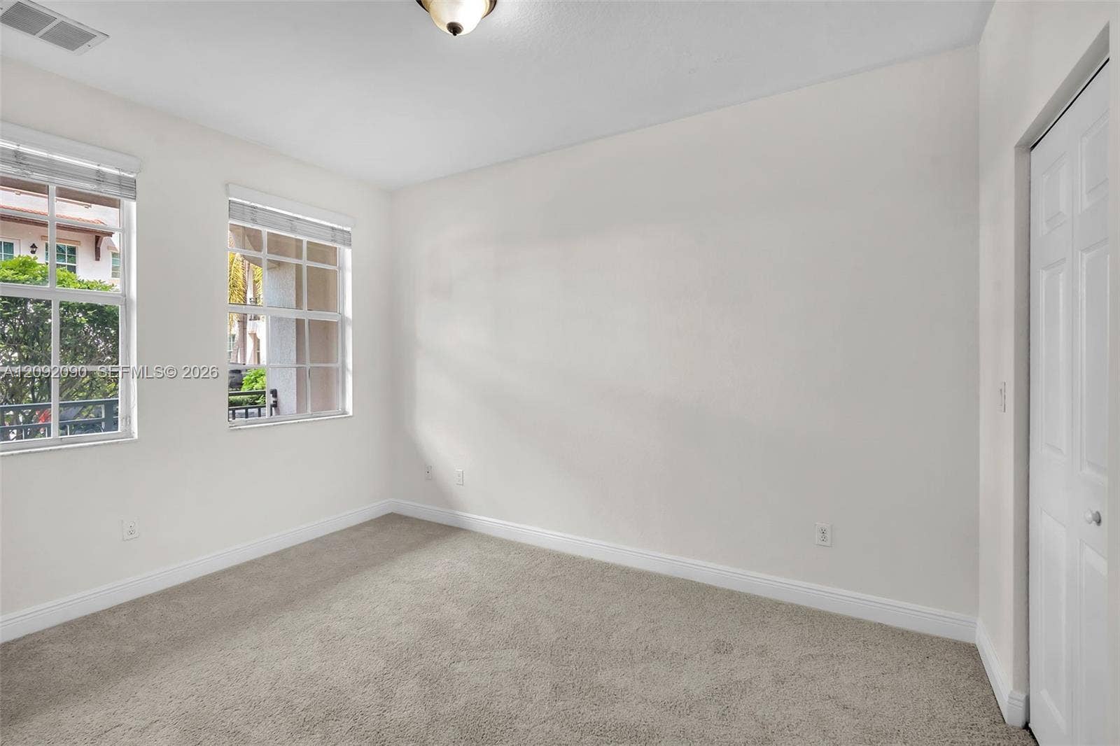 11979 SW 28th Court, Miramar, Miramar, FL 33025 Neutral interior space featuring carpeting, two grid-patterned windows, a flush-mount ceiling light fixture, and a white interior door