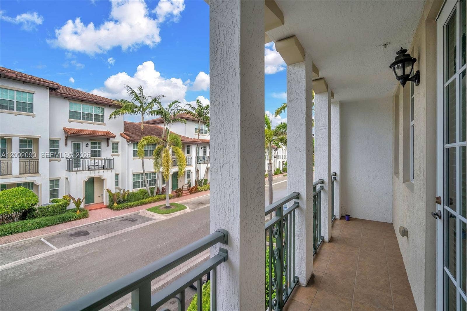 11979 SW 28th Court, Miramar, Miramar, FL 33025 Covered balcony featuring tile flooring, structural stucco columns, dark metal railings, and a wall-mounted exterior light fixture