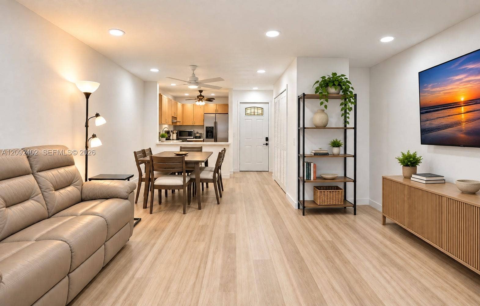 499 SE 13th Street, #7E, Fort Lauderdale, FL 33316 TV console & plants virtually staged for illustrative purposes. Open-concept interior featuring light wood-finish flooring, recessed lighting, white cabinetry, and an exterior entry door with an arched glass inset