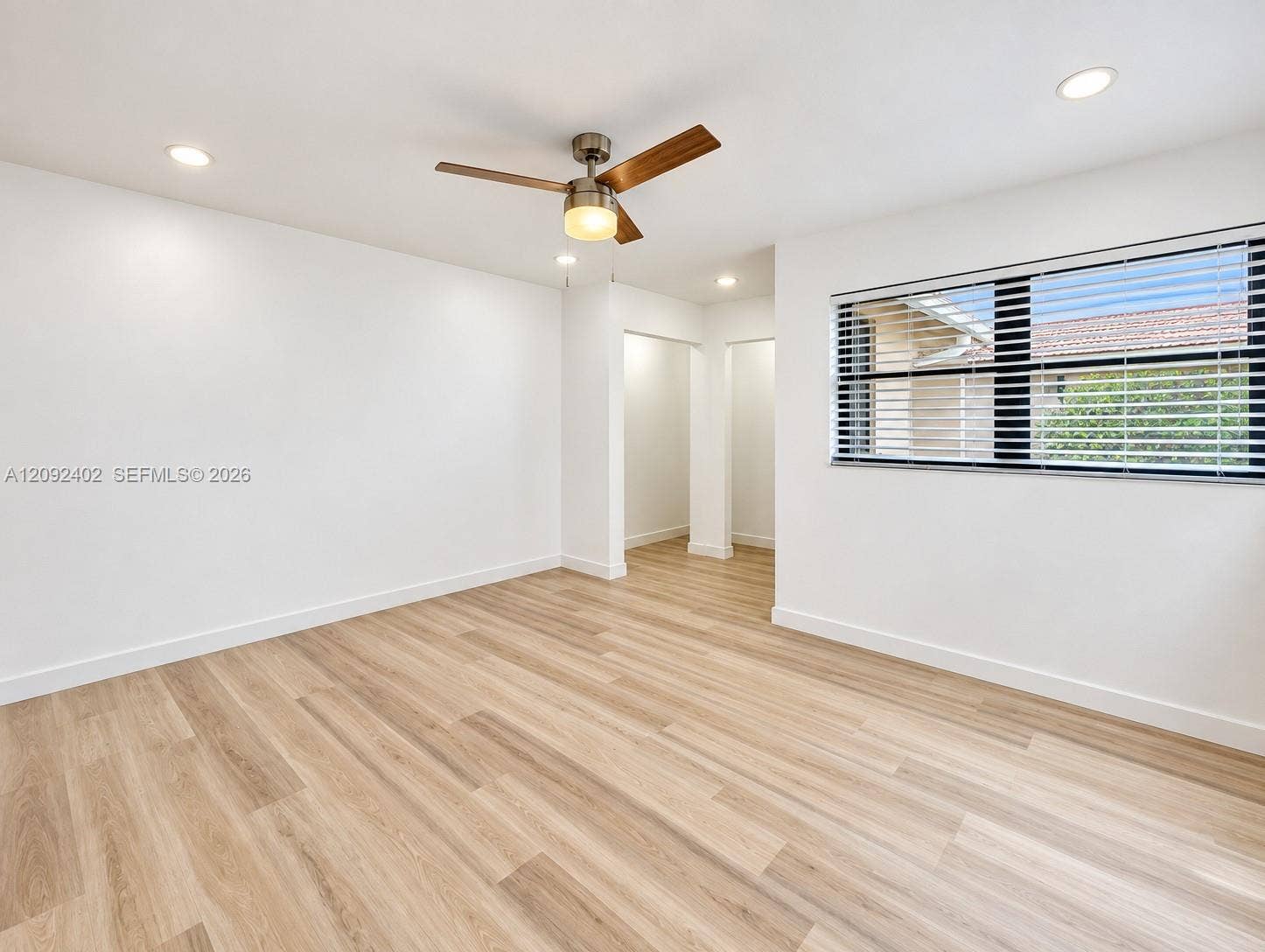 499 SE 13th Street, #7E, Fort Lauderdale, FL 33316 Neutral interior space featuring wood-finish flooring, recessed lighting, a modern ceiling fan with light fixture, and large windows with horizontal blinds