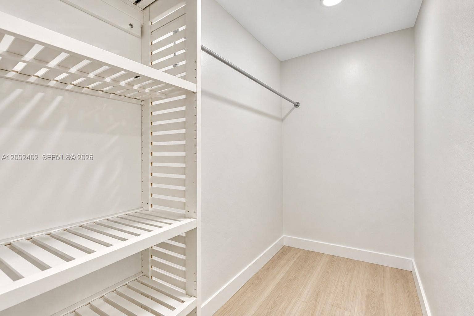 499 SE 13th Street, #7E, Fort Lauderdale, FL 33316 Walk-in closet featuring white slatted built-in shelving, a metal hanging rod, and wood-finish flooring