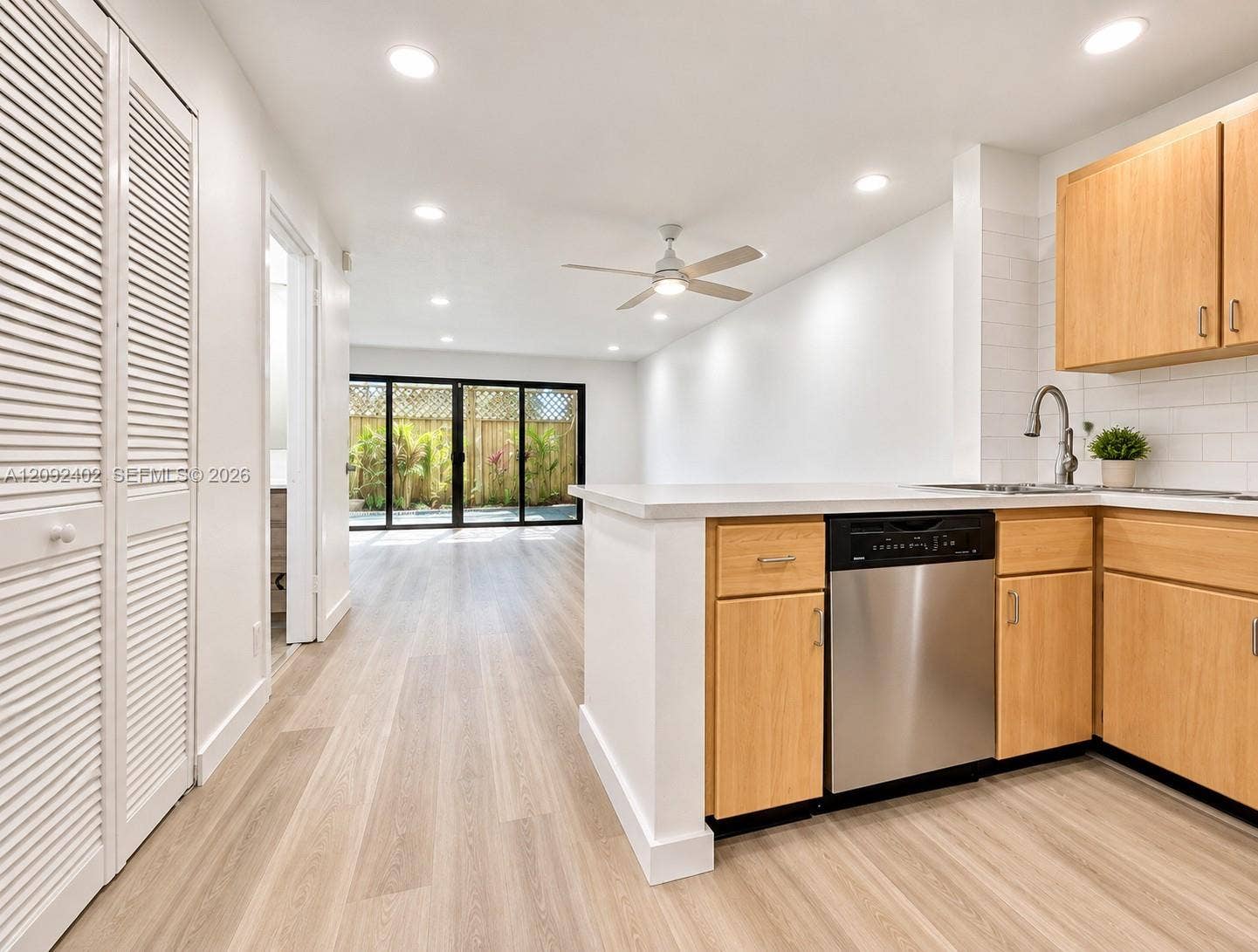 499 SE 13th Street, #7E, Fort Lauderdale, FL 33316 Kitchen featuring wood-finish cabinetry, stainless steel dishwasher, light-toned wood-finish flooring, recessed lighting, and floor-to-ceiling multi-panel sliding glass doors