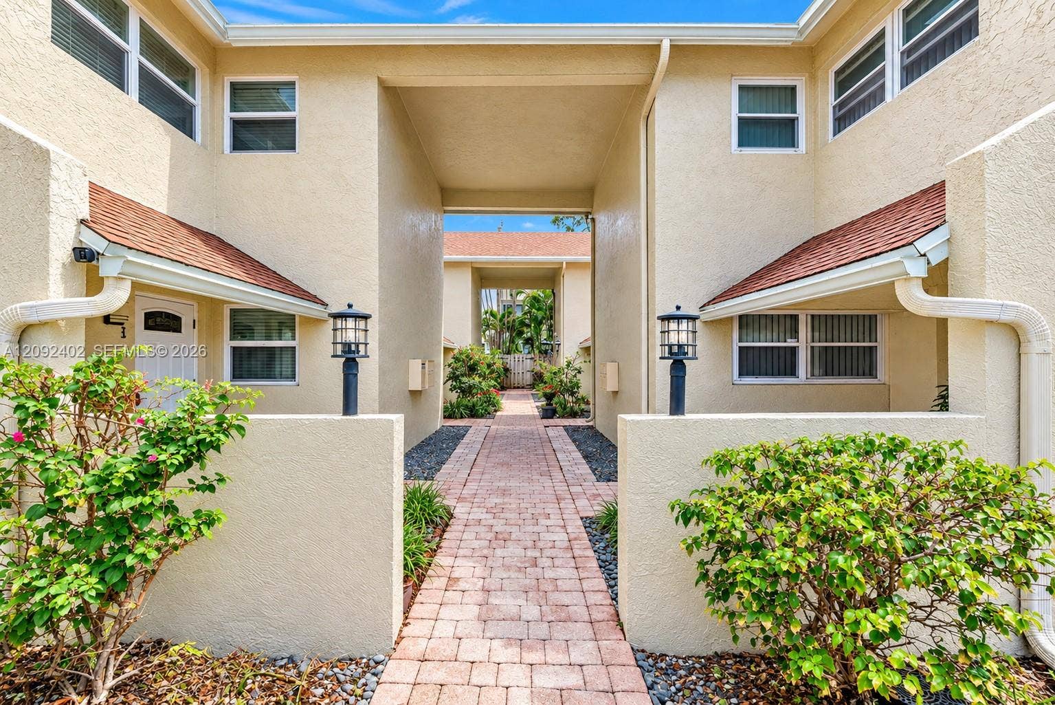499 SE 13th Street, #7E, Fort Lauderdale, FL 33316 Stucco exterior featuring a paved brick walkway, decorative post lighting, and shingle roofing