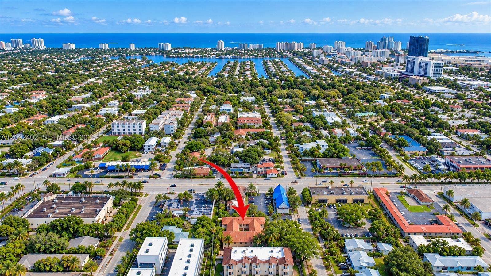 499 SE 13th Street, #7E, Fort Lauderdale, FL 33316 Aerial perspective of a multi-story building featuring a tile roof, centered courtyard, and surrounding mature landscaping