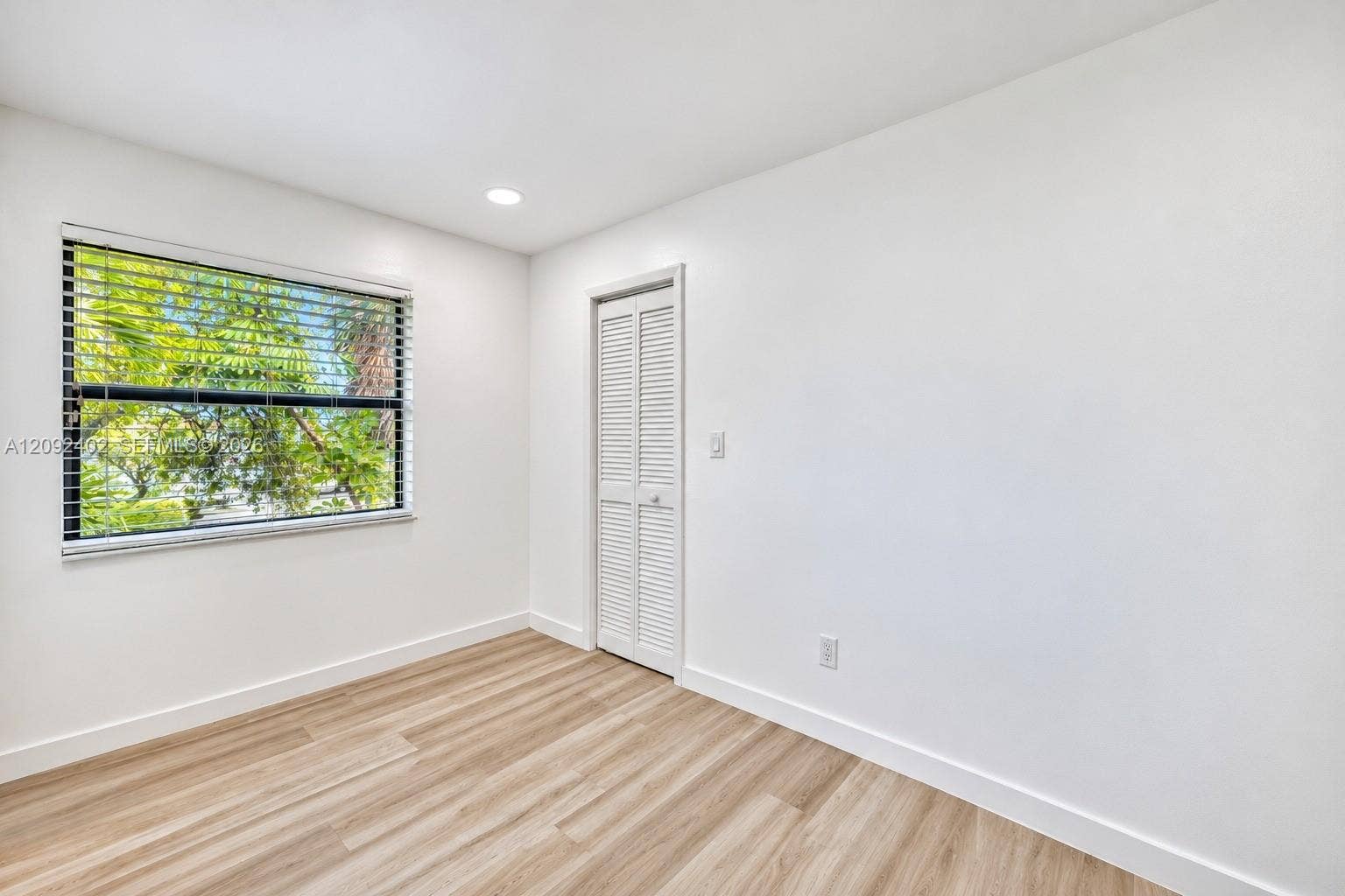 499 SE 13th Street, #7E, Fort Lauderdale, FL 33316 Neutral-toned room featuring wood-finish flooring, white walls, recessed ceiling lighting, and a louvered closet door