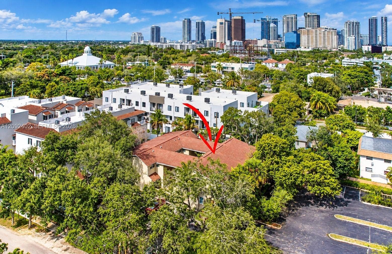 499 SE 13th Street, #7E, Fort Lauderdale, FL 33316 Aerial perspective of a multi-unit residential structure featuring a central courtyard, shingled roofing, and a dedicated asphalt parking area surrounded by mature trees