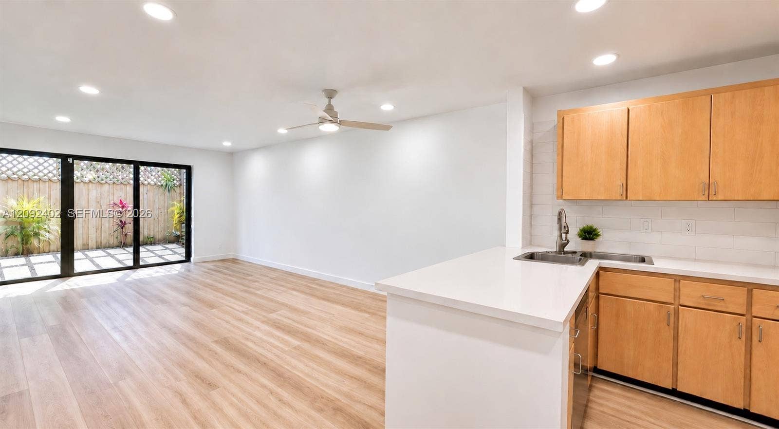 499 SE 13th Street, #7E, Fort Lauderdale, FL 33316 Kitchen featuring wood-finish cabinetry, white countertops, and subway tile backsplash, complemented by wood-finish flooring, recessed lighting, and sliding glass doors