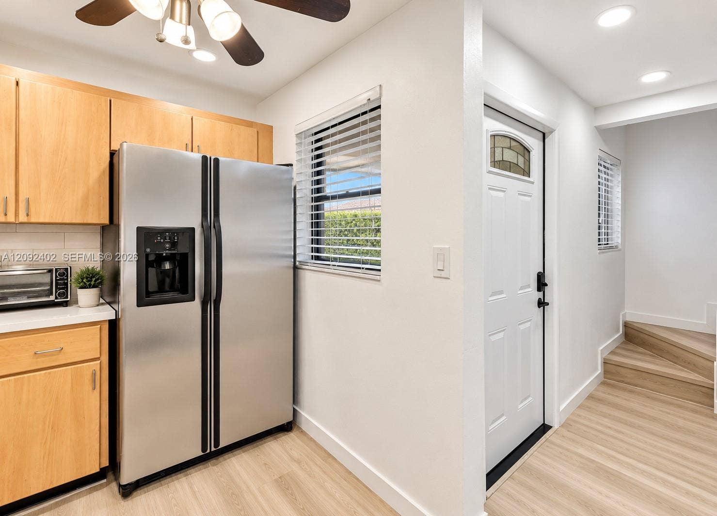 499 SE 13th Street, #7E, Fort Lauderdale, FL 33316 Kitchen featuring light-finish cabinetry, stainless steel side-by-side refrigerator, recessed lighting, wood-finish flooring, and a white exterior entry door with a decorative glass insert