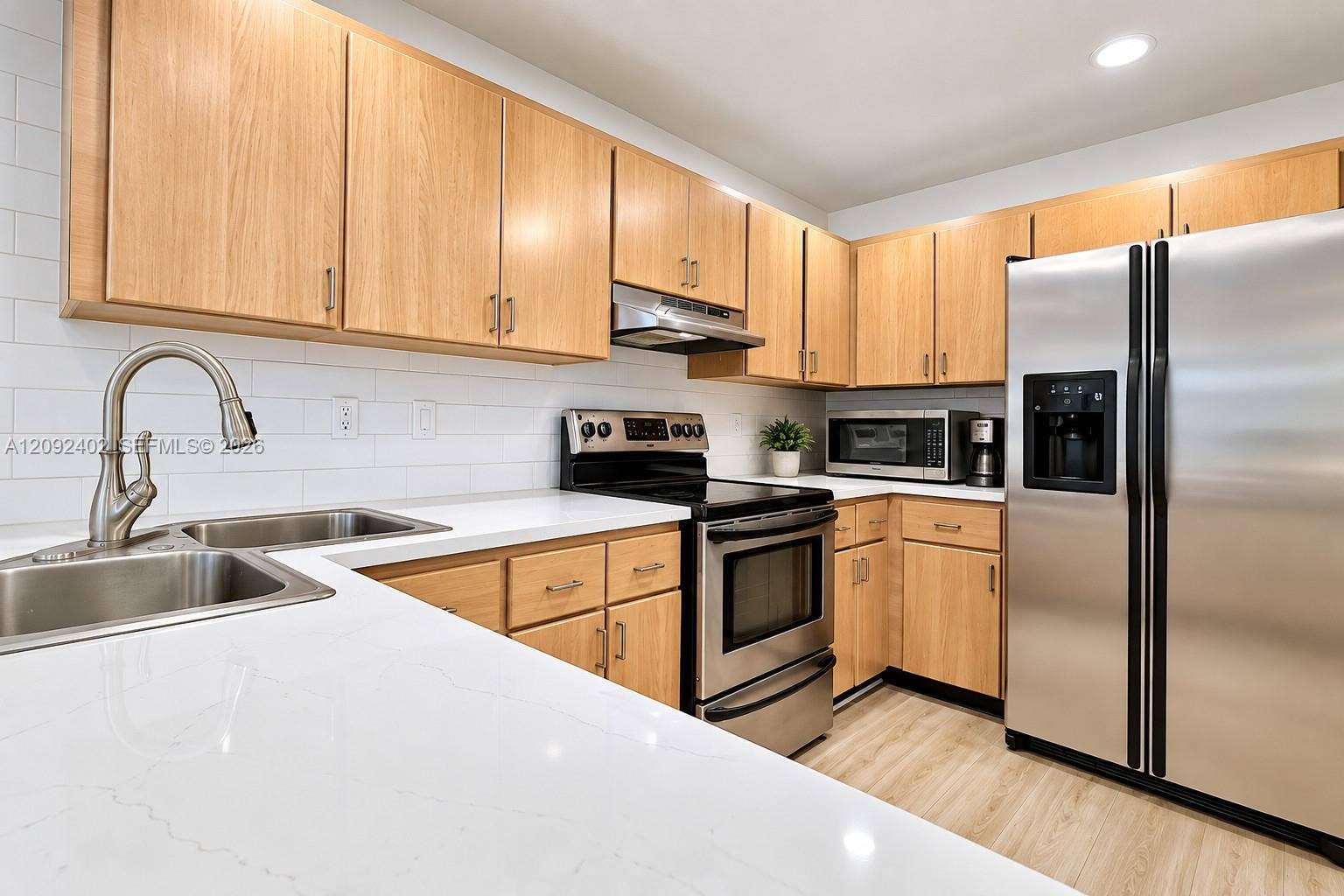 499 SE 13th Street, #7E, Fort Lauderdale, FL 33316 Kitchen featuring natural wood-finish cabinetry, white solid-surface countertops, subway tile backsplash, stainless steel appliances, and recessed lighting