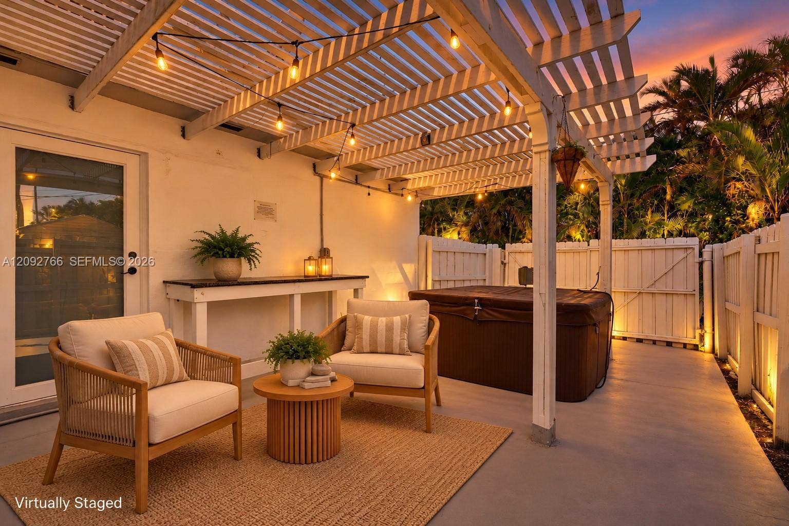 Covered patio area featuring a wooden pergola, concrete flooring, built-in wooden console table, and a private hot tub enclosed by perimeter fencing
