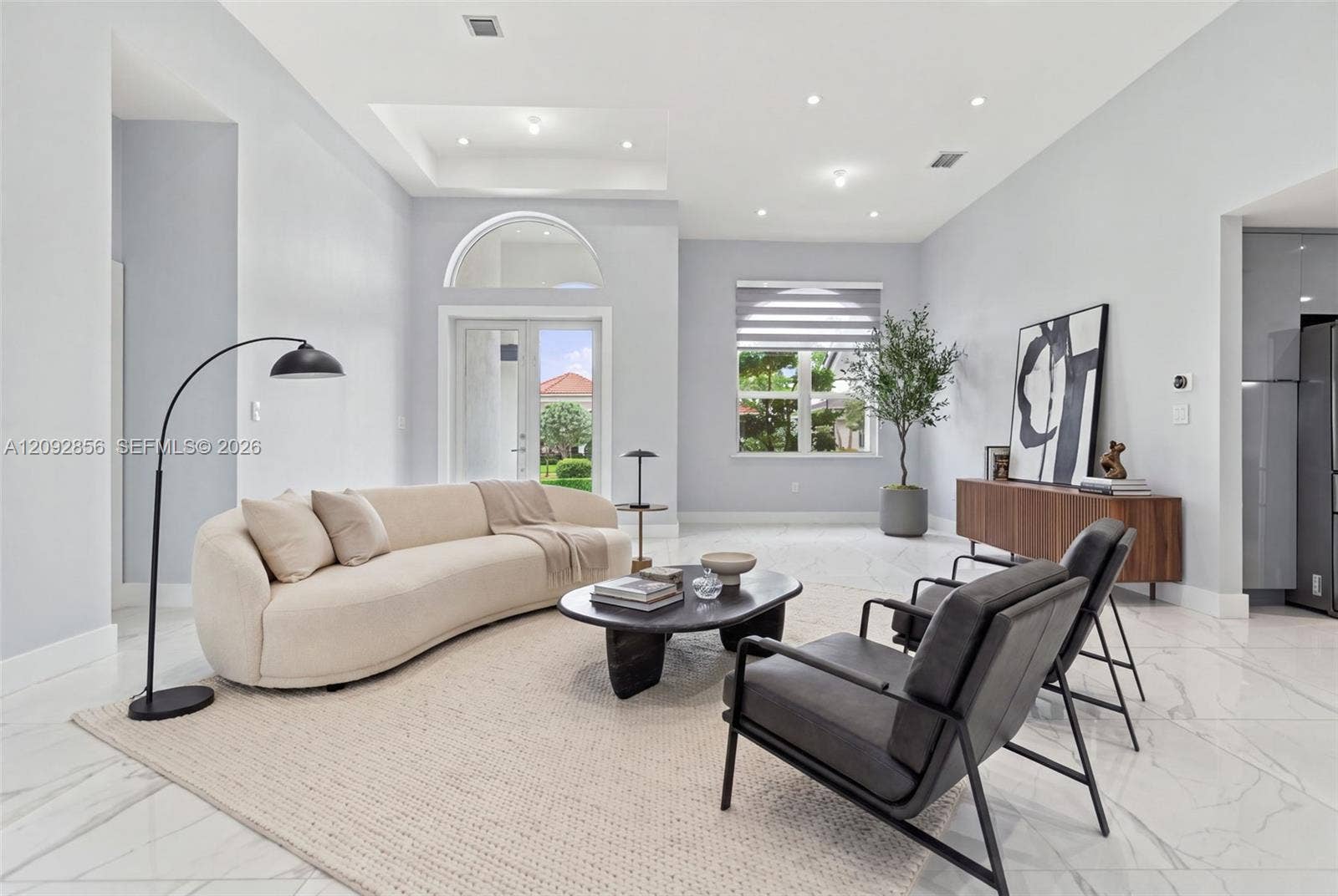 18919 SW 24th Street, #18919, Miramar, Miramar, FL 33029 Virtually staged - Living area featuring a double-tray ceiling, recessed lighting, arched transom window, glass-paneled door, and large-format tile flooring
