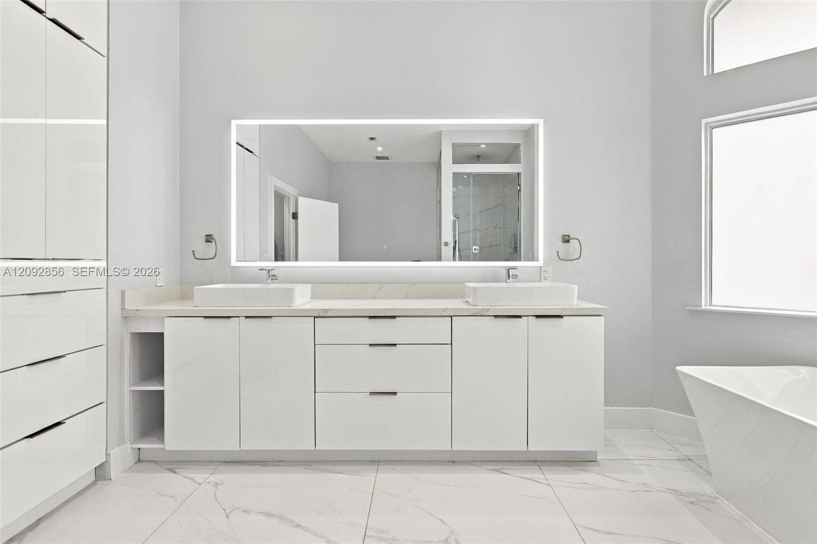 18919 SW 24th Street, #18919, Miramar, Miramar, FL 33029 Bathroom featuring a dual-sink vanity with matte white cabinetry, stone-surface countertop, rectangular vessel sinks, an expansive LED-backlit mirror, and large-format porcelain floor tile