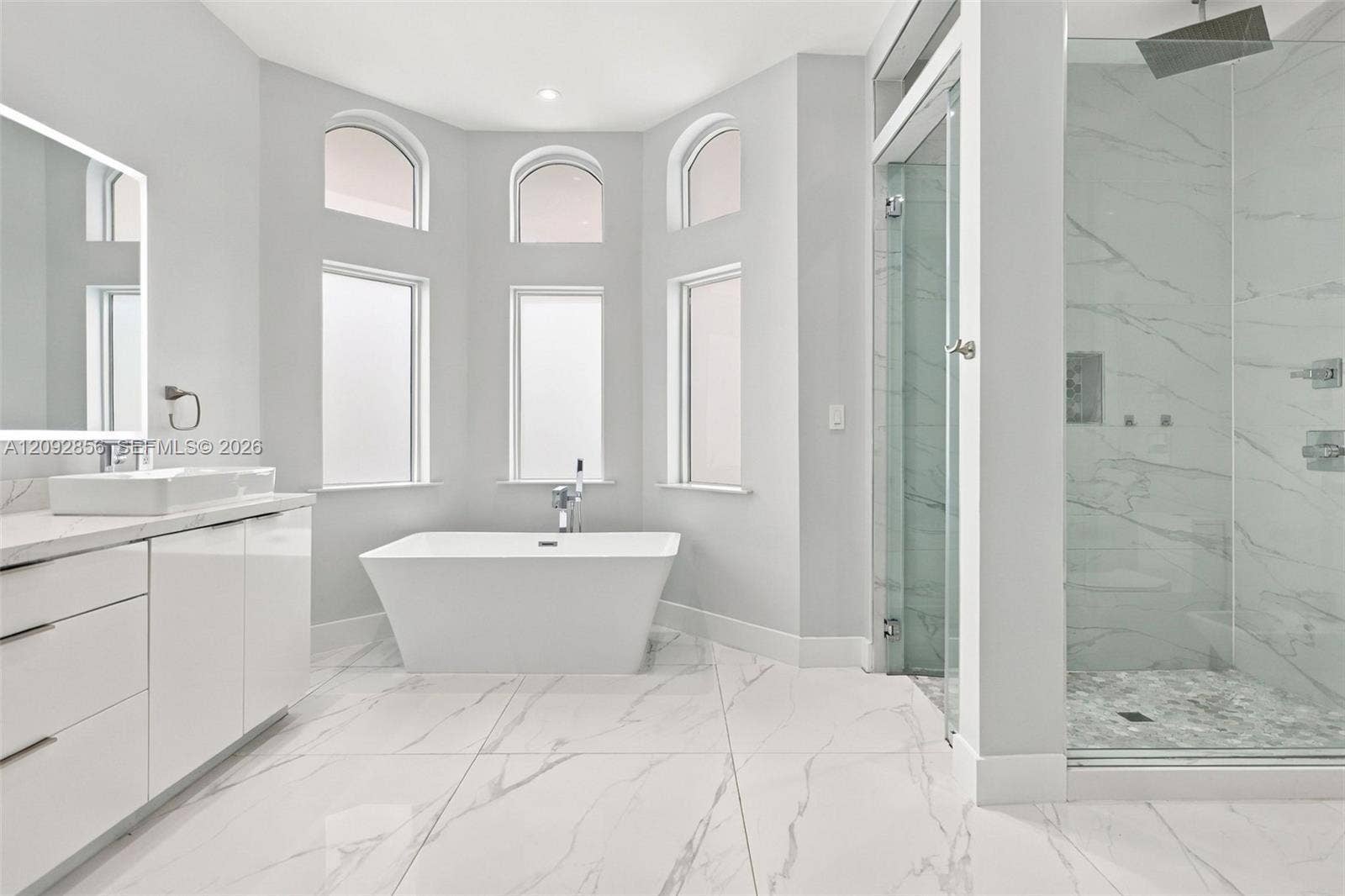 18919 SW 24th Street, #18919, Miramar, Miramar, FL 33029 Freestanding soaking tub set in a bay alcove with arched windows, large-format tile flooring, frameless glass-enclosed shower, and sleek vanity with a vessel sink
