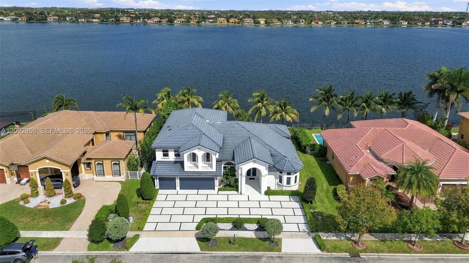 18919 SW 24th Street, #18919, Miramar, Miramar, FL 33029 Waterfront property featuring a multi-gabled roofline, light-toned exterior finish, paver-style driveway, and an expansive rear lawn