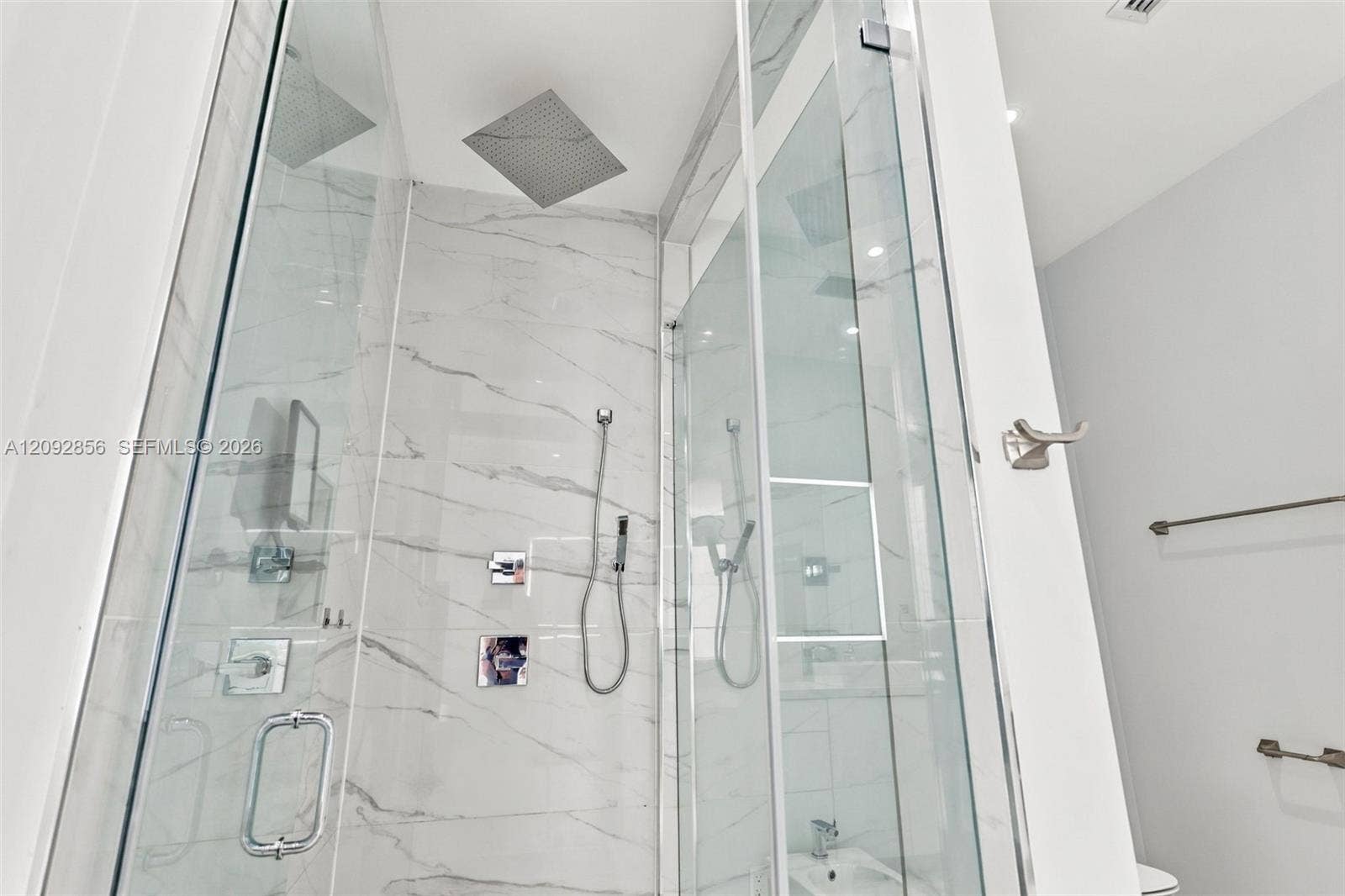 18919 SW 24th Street, #18919, Miramar, Miramar, FL 33029 Glass-enclosed walk-in shower featuring floor-to-ceiling stone-finish tile, a square rainfall showerhead, a separate handheld sprayer, and polished chrome fixtures