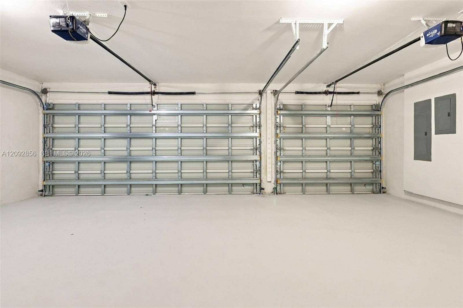 18919 SW 24th Street, #18919, Miramar, Miramar, FL 33029 Two-car garage featuring dual overhead automatic openers, neutral flooring, and wall-mounted electrical panels