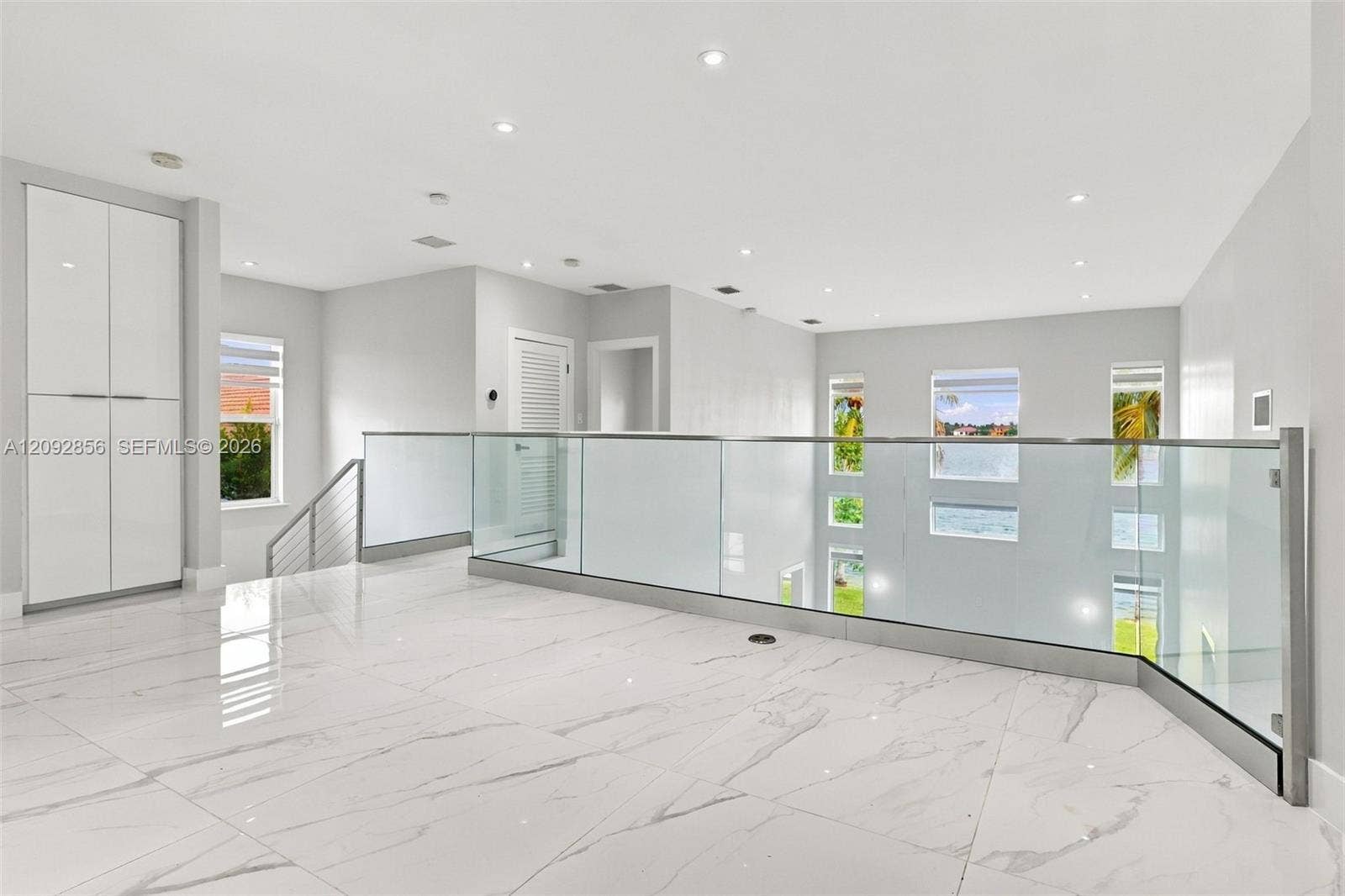 18919 SW 24th Street, #18919, Miramar, Miramar, FL 33029 Open landing featuring high-gloss large-format tile flooring, glass panel railing with metallic hardware, recessed ceiling lighting, and floor-to-ceiling built-in cabinetry