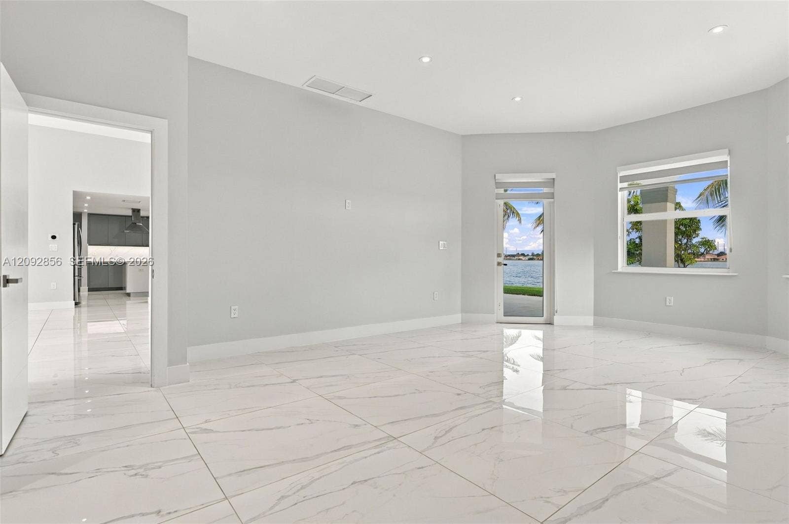 18919 SW 24th Street, #18919, Miramar, Miramar, FL 33029 Polished stone-finish flooring, recessed lighting, neutral wall paint, and full-glass exterior door with waterfront scenery and access to back patio.