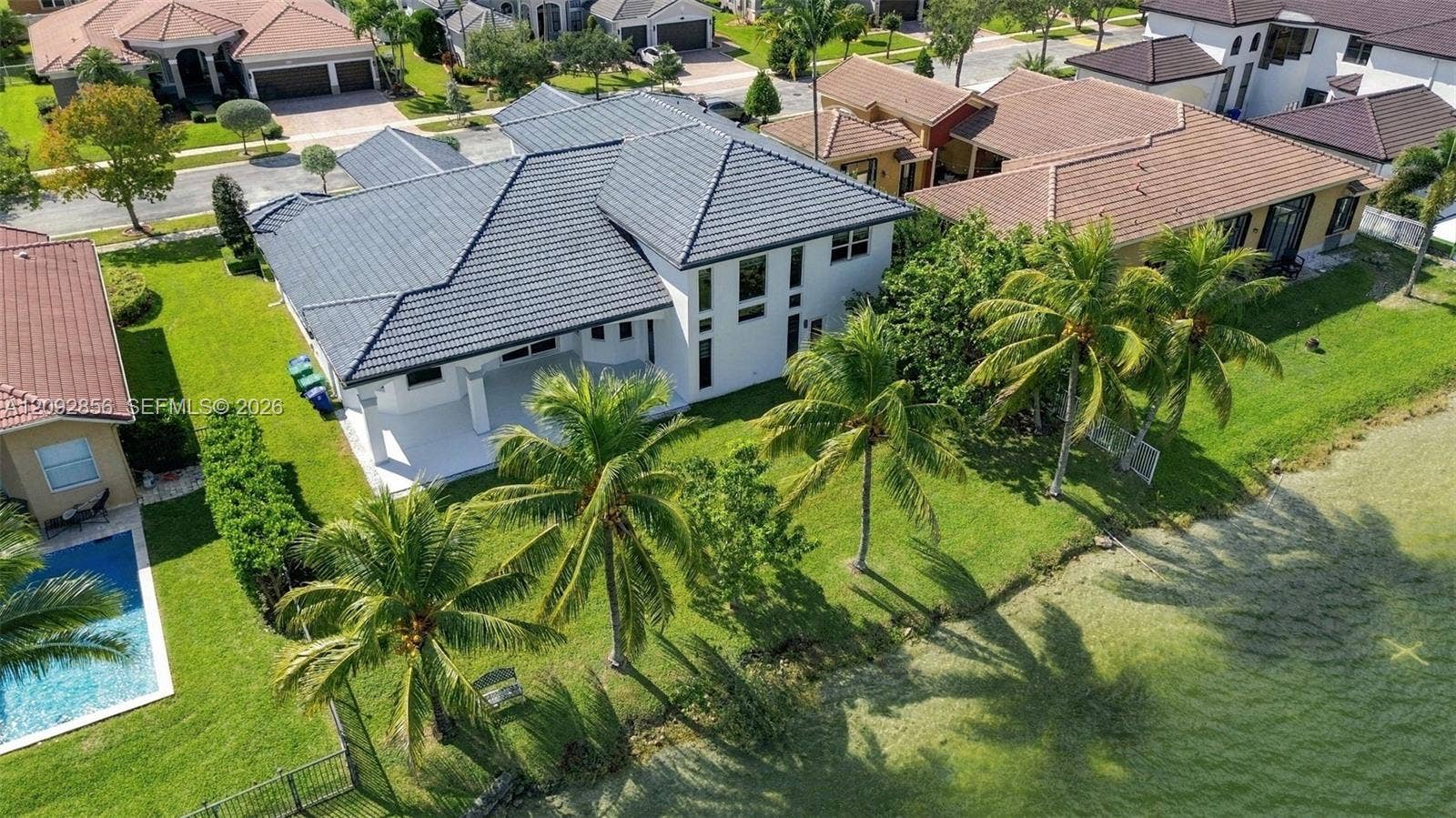 18919 SW 24th Street, #18919, Miramar, Miramar, FL 33029 Multi-level residence featuring a tile roof, expansive rear patio, manicured lawn, and waterfront lot with mature palm trees